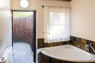 a bathroom with a large tub and a shower at Phalaborwa Safari Park, A Forever Resort in Phalaborwa