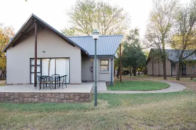 a house with a table and chairs in front of it at Phalaborwa Safari Park, A Forever Resort in Phalaborwa