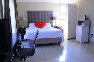 a bedroom with a bed with a heart pillow and a chair at Lullaby Guesthouse in Tzaneen