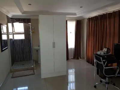 a hotel room with a corridor with a door and a desk at Lullaby Guesthouse in Tzaneen
