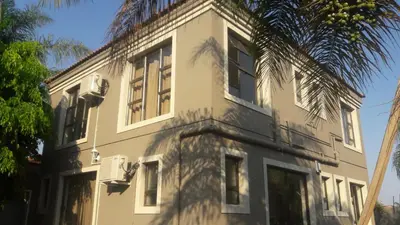 a white building with a palm tree in front of it at Lullaby Guesthouse in Tzaneen