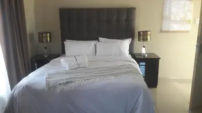 a bedroom with a large white bed with two night stands at Lullaby Guesthouse in Tzaneen