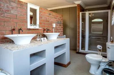 a bathroom with two sinks and a brick wall at Klip en Kristal Guest House in Bela-Bela