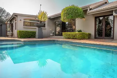 a swimming pool in front of a house at Klip en Kristal Guest House in Bela-Bela
