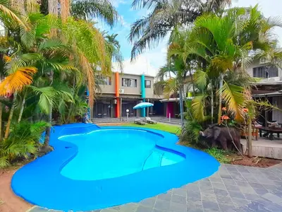 a pool in front of a resort with palm trees at Elephant Springs in Bela-Bela