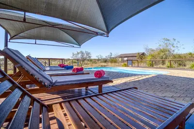 a patio with chairs and an umbrella next to a swimming pool at Abendruhe Lodge in Pretoria