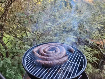 a coil of sausage cooking on a grill at Suikerbosrant Sleep and go in Pretoria