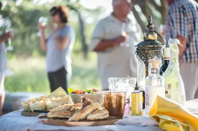 a table with food on it with people in the background at Makuwa Safari Lodge in Mbabat