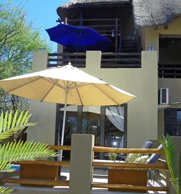 two umbrellas sitting on a table in front of a building at Marloth Park Hippo House in Marloth Park