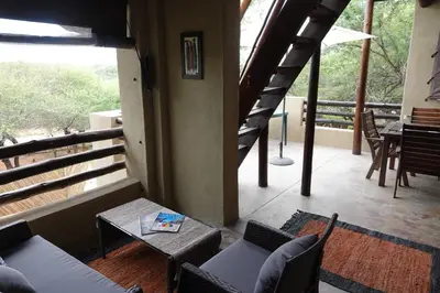 a room with a balcony with chairs and a table at Marloth Park Hippo House in Marloth Park