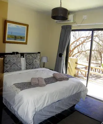 a bedroom with a bed and a large window at Marloth Park Hippo House in Marloth Park