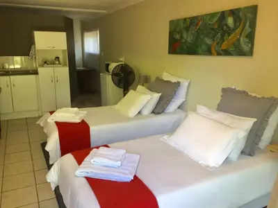 a room with three beds with towels on them at Green Fields Cottage in Nelspruit