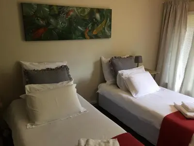 a bedroom with two beds and a painting on the wall at Green Fields Cottage in Nelspruit