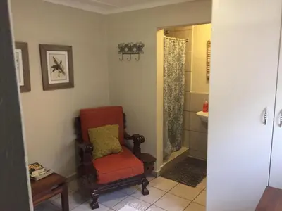 a bathroom with a red chair and a shower at Green Fields Cottage in Nelspruit