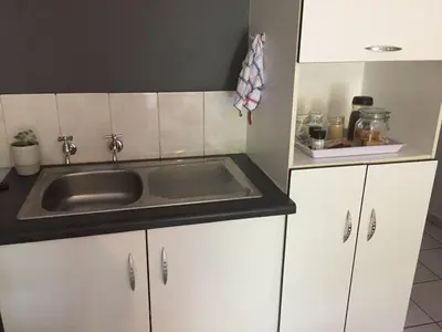 a kitchen with a sink and white cabinets at Green Fields Cottage in Nelspruit