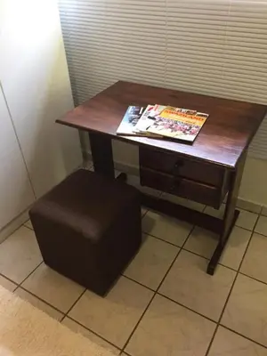a wooden table with a magazine and a stool at Green Fields Cottage in Nelspruit