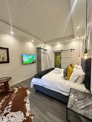 a bedroom with a bed and a tv on the wall at Spacube Luxury Suites and Spa in Pretoria