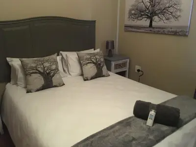 a bedroom with a white bed with trees on it at Esmarline Lodge in Brits
