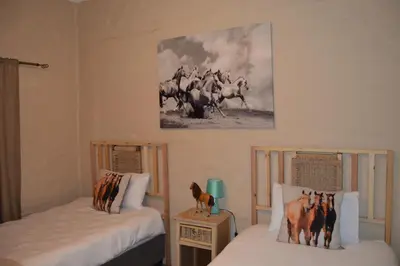 two beds in a room with horses on the wall at Esmarline Lodge in Brits