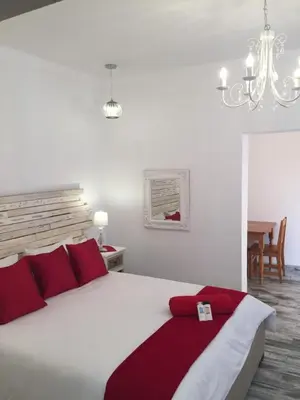 a bedroom with a large white bed with red pillows at Esmarline Lodge in Brits