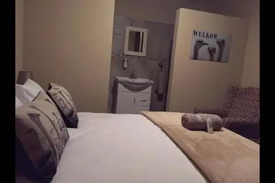 a bedroom with a white bed and a sink at Esmarline Lodge in Brits
