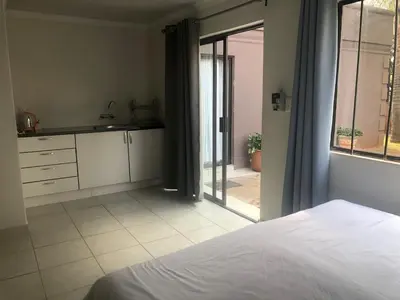a bedroom with a bed and a view of a patio at Africaren Budget Stay in Kempton Park