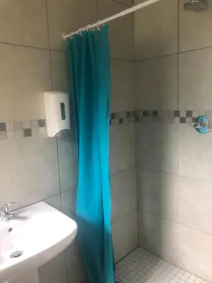 a shower with a blue shower curtain next to a sink at Africaren Budget Stay in Kempton Park