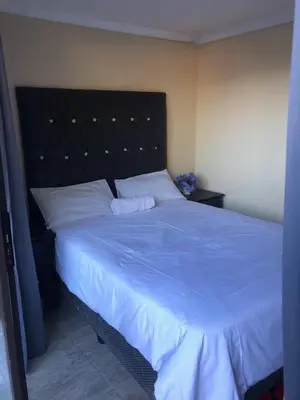 a bedroom with a large bed with a blue blanket at Africaren Budget Stay in Kempton Park