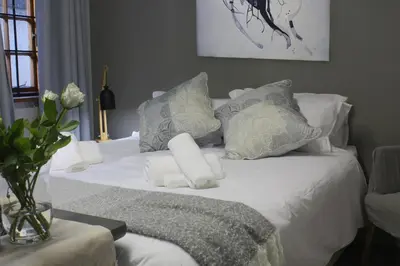a white bed with towels and a vase with flowers on it at 31 at Murray in Pretoria