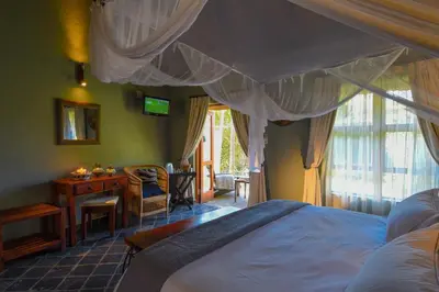a bedroom with a bed and a desk and a window at La Lechere Guest House in Phalaborwa
