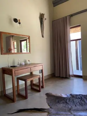 a room with a wooden table and a mirror at La Lechere Guest House in Phalaborwa