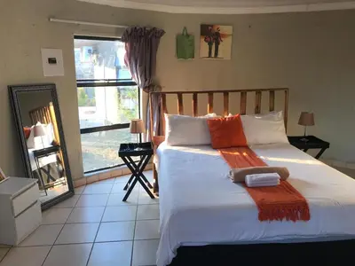 a bedroom with a bed with an orange blanket on it at Rhurhy Guest House in Acornhoek