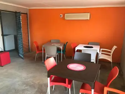 a dining room with tables and chairs and an orange wall at Rhurhy Guest House in Acornhoek