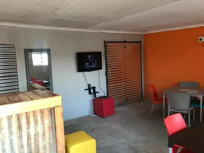 a living room with a table and a tv on the wall at Rhurhy Guest House in Acornhoek