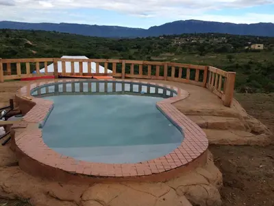 a large swimming pool with a wooden fence around it at Rhurhy Guest House in Acornhoek