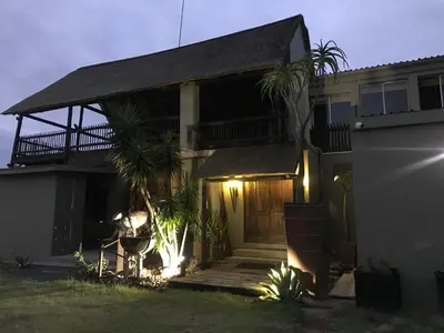a house with a porch and a balcony at night at Sunset Lodge & Safaris in Guernsey Nature Reserve