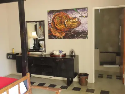a bedroom with a dresser and a painting on the wall at Sunset Lodge & Safaris in Guernsey Nature Reserve