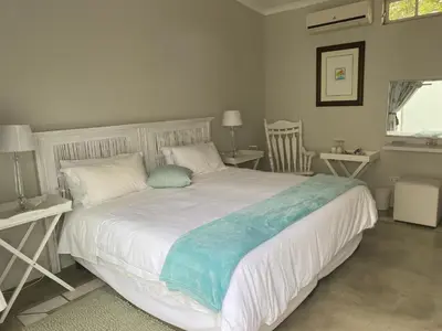 a bedroom with a large white bed with a blue blanket at Sunset Lodge & Safaris in Guernsey Nature Reserve