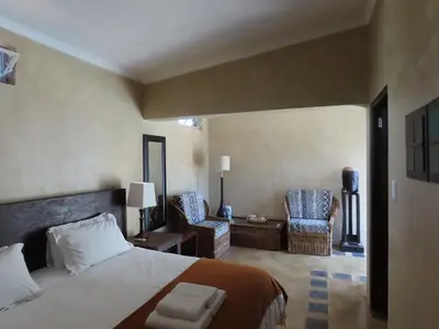 a bedroom with a bed and two chairs in it at Sunset Lodge & Safaris in Guernsey Nature Reserve