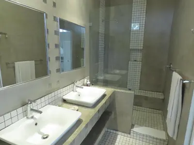 a bathroom with two sinks and a shower at Sunset Lodge & Safaris in Guernsey Nature Reserve