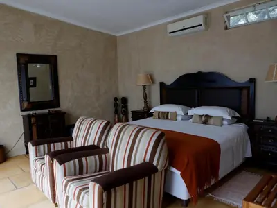a bedroom with a large bed and two chairs at Sunset Lodge & Safaris in Guernsey Nature Reserve
