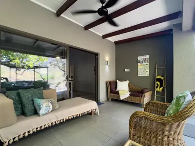 a living room with a couch and chairs and a ceiling fan at Birds Babble Self Catering in Nelspruit