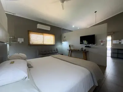 a bedroom with a large white bed and a television at Birds Babble Self Catering in Nelspruit