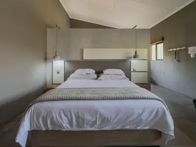 a bedroom with a large bed with white sheets and pillows at Birds Babble Self Catering in Nelspruit