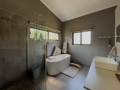 a bathroom with a tub and a shower and a sink at Birds Babble Self Catering in Nelspruit