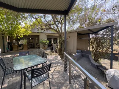 a patio with a table and chairs and a grill at Birds Babble Self Catering in Nelspruit