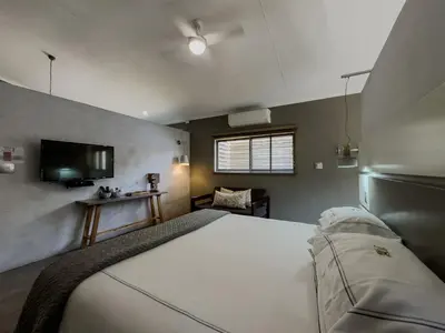 a bedroom with a large white bed and a television at Birds Babble Self Catering in Nelspruit
