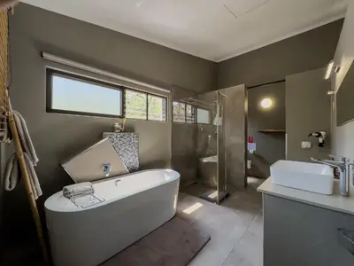 a bathroom with a tub and a shower and a sink at Birds Babble Self Catering in Nelspruit