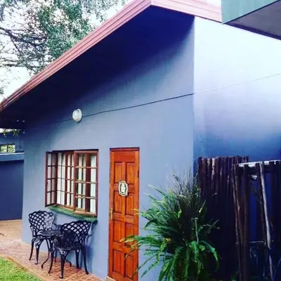 a blue building with a door and a table and chairs at Mount Azimbo Lodge in Louis Trichardt