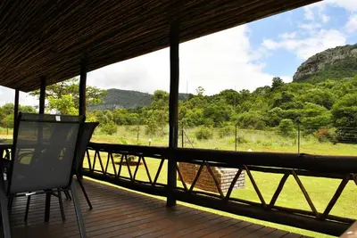 a porch with a chair and a view of a river at Mount Azimbo Lodge in Louis Trichardt